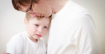 father comforting his crying little son - parenthood concept